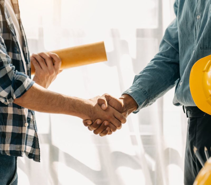 Müteahhitlik Construction team shake hands greeting start new project plan behind yellow helmet on desk in modern office center to consults about their building project.